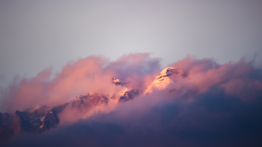 a mountain covered in pink clouds in the distance
