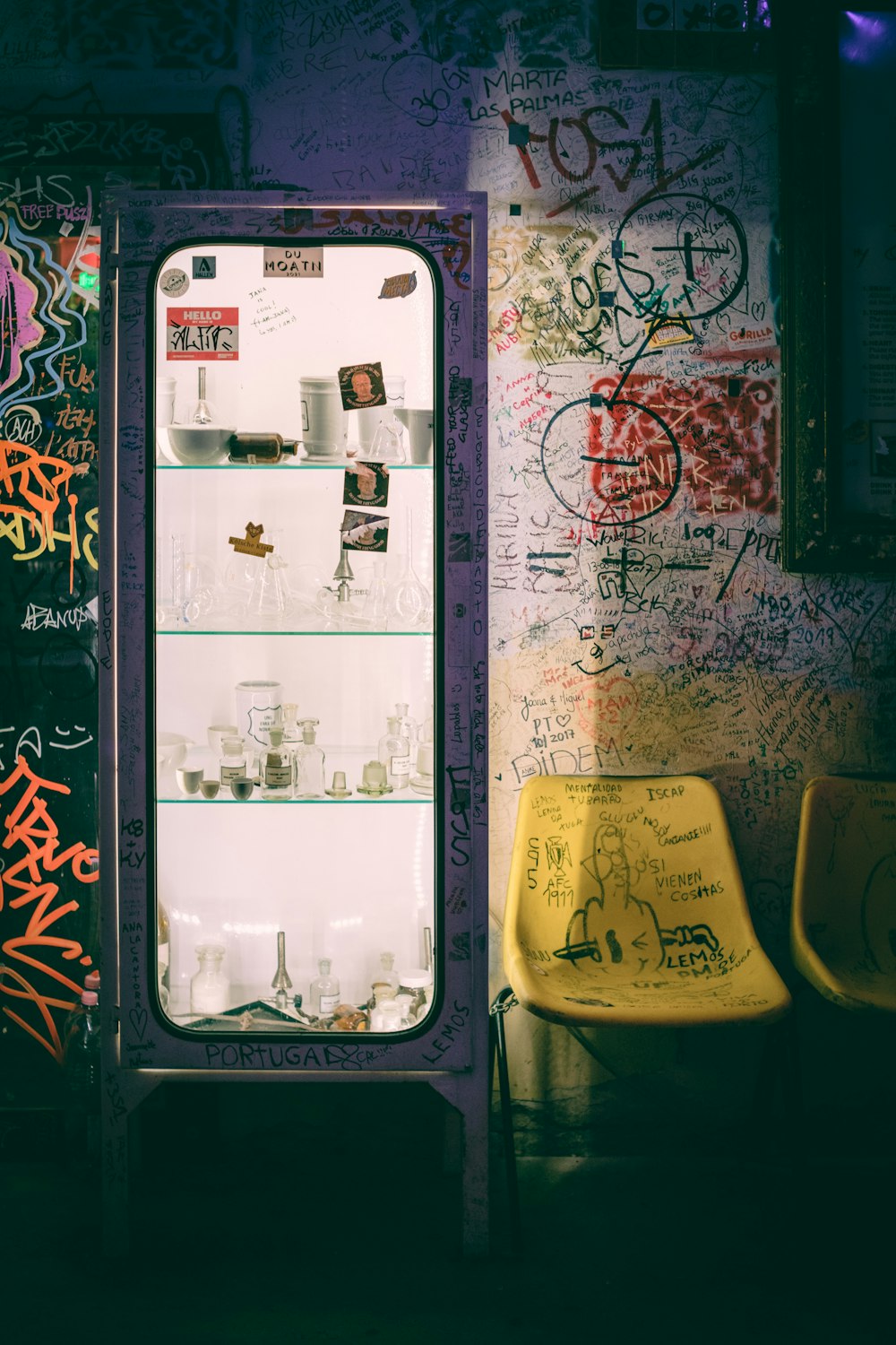 a refrigerator sitting in front of a wall covered in graffiti