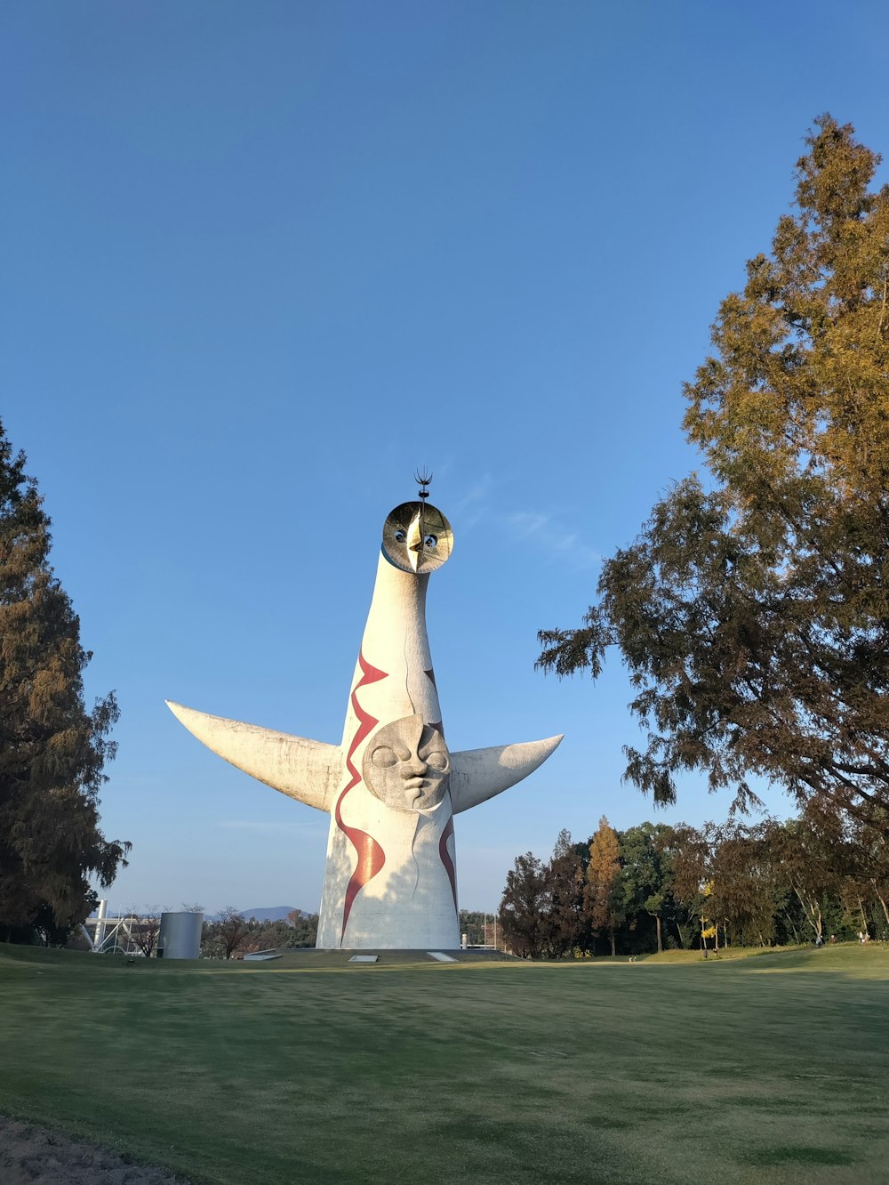 a large white bird statue sitting on top of a lush green field