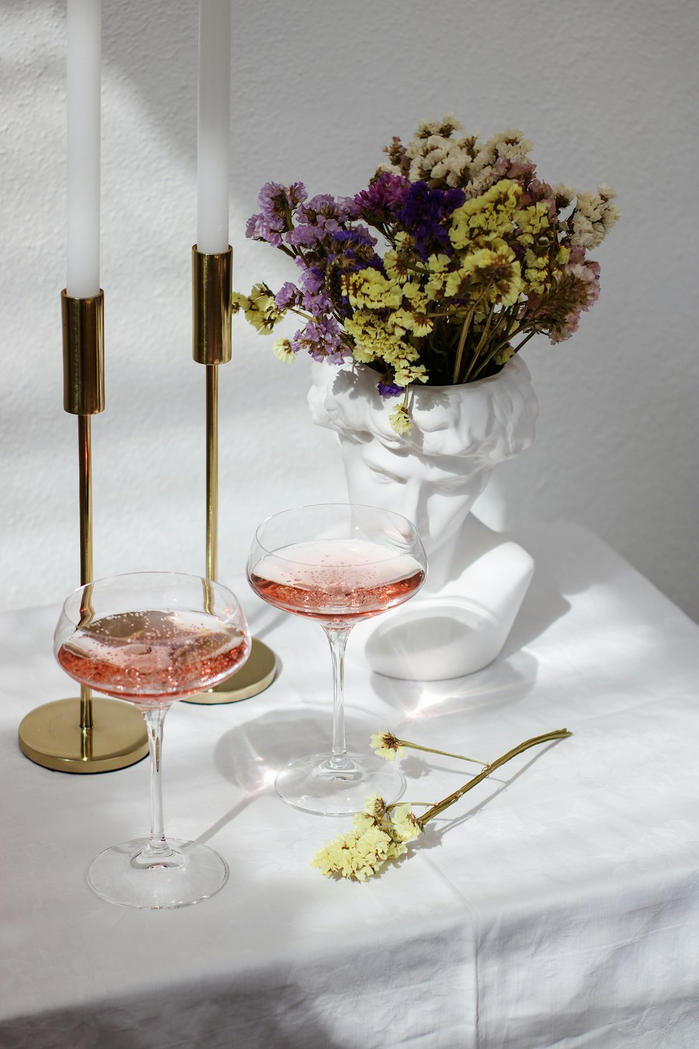 uma mesa coberta com dois copos de vinho e um vaso cheio de flores