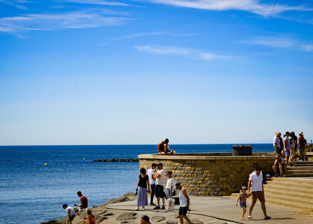 a group of people standing on top of a pier next to the ocean