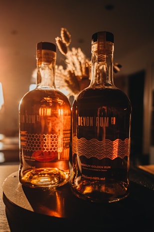 Elegant bottle of spiced rum with cinnamon sticks and vanilla pods alongside.