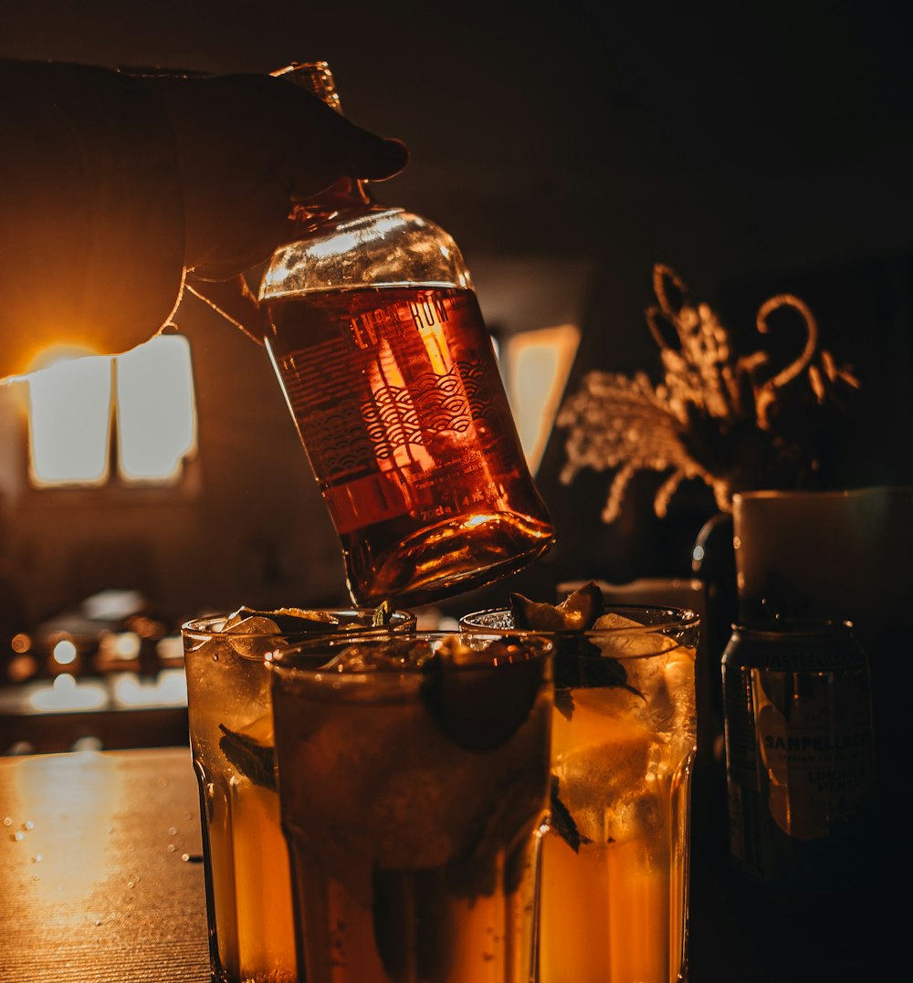 a person pouring a drink into a glass