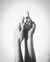 An intimate black and white photo of hands intertwined during a wedding.