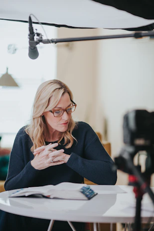 a woman sitting at a table in front of a camera