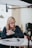 a woman sitting at a table in front of a camera