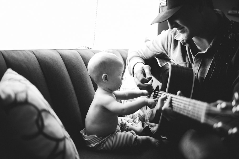 a man playing a guitar for a baby