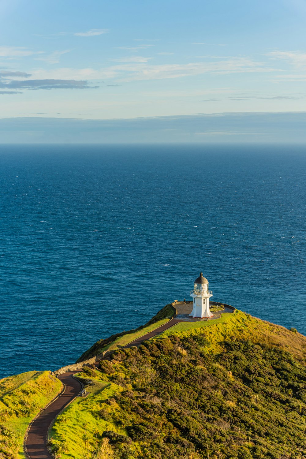 um farol no topo de uma colina com vista para o oceano