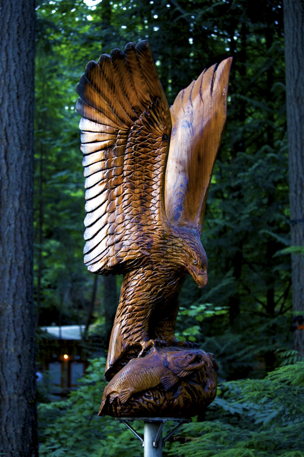a statue of an eagle is in the middle of a forest