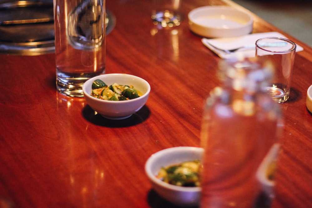 a wooden table topped with bowls of food