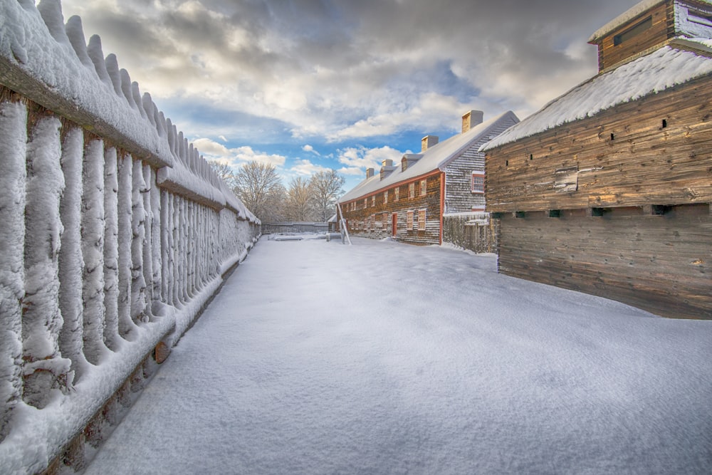 a snow covered sidewalk next to a wooden building