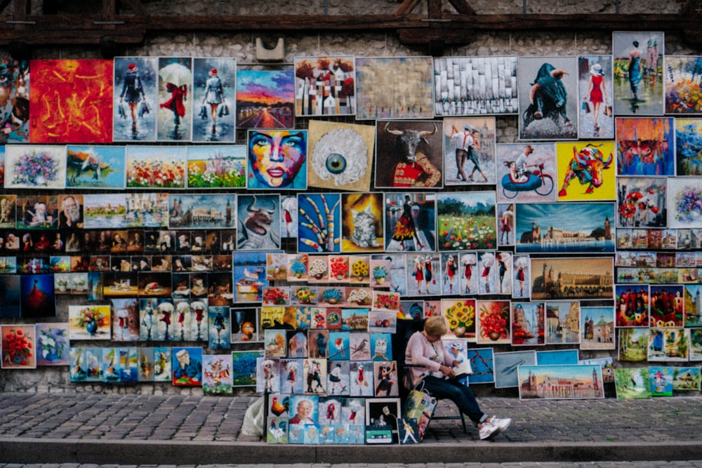 a person sitting on a bench in front of a wall covered with pictures
