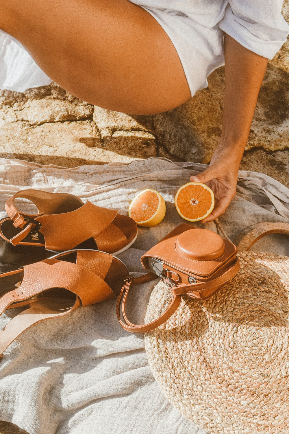 a woman is sitting on a bed with a straw hat and orange slices