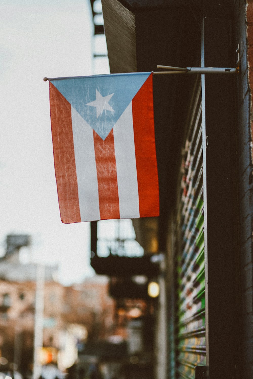 a flag hanging from a building on the side of a street