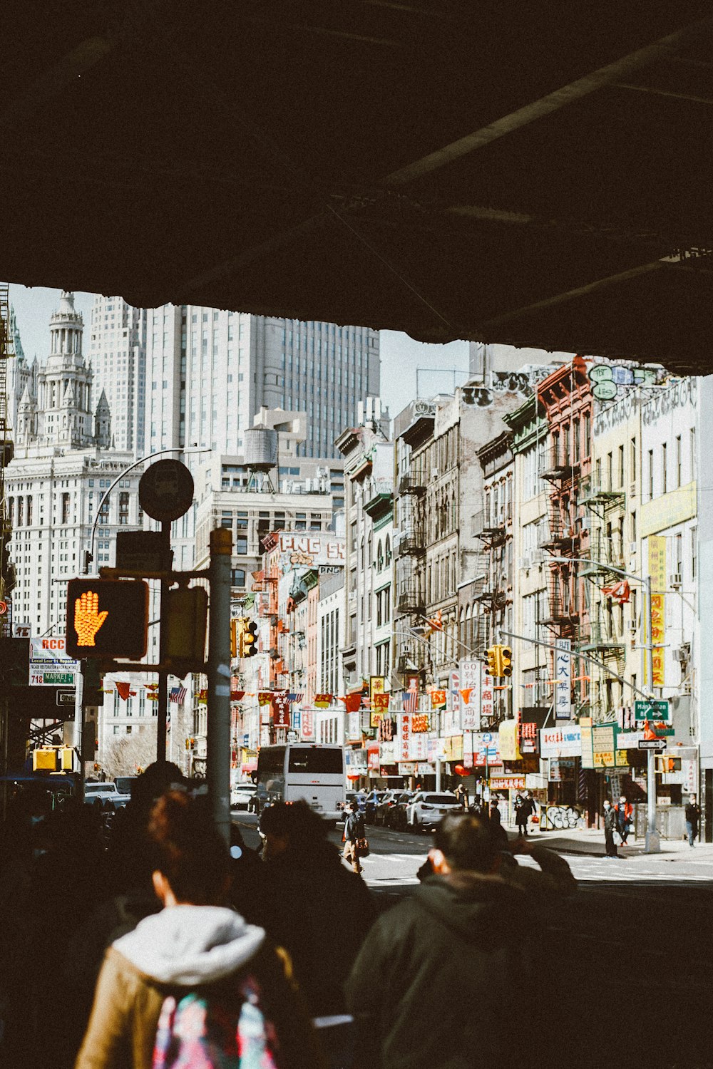 a group of people walking down a street next to tall buildings