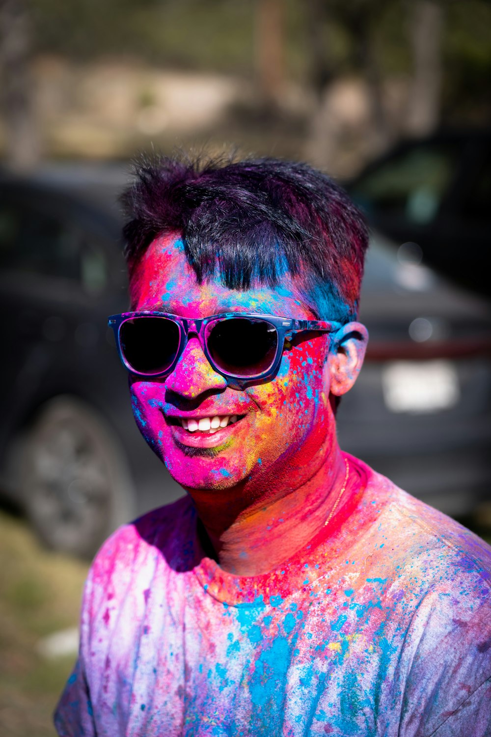 a man wearing sunglasses and a shirt covered in colored powder
