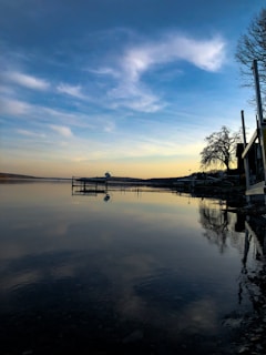 A serene lakeside view at sunset with warm orange and blue tones reflecting on the water.