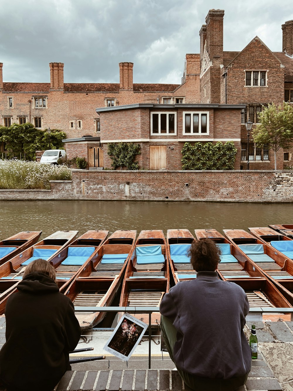 a couple of people sitting on a dock next to a body of water