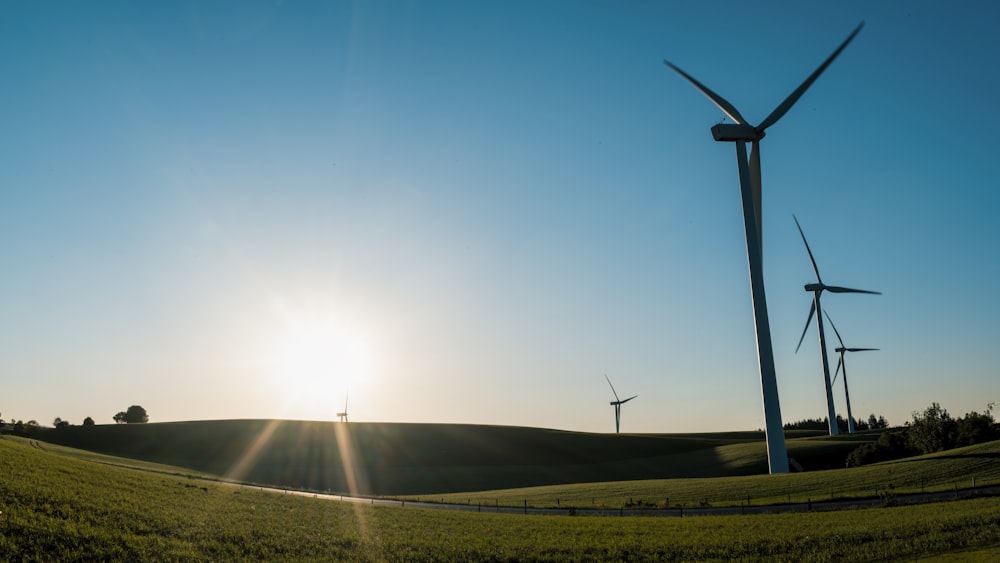 the sun is setting behind a row of windmills