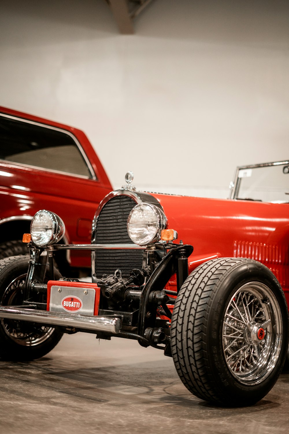 a red car parked in a garage next to a red truck