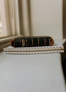 An old, worn-out black Holy Bible with frayed edges rests on top of a spiral-bound notebook. The objects are placed on a light-colored surface near a window, allowing soft natural light to illuminate them.