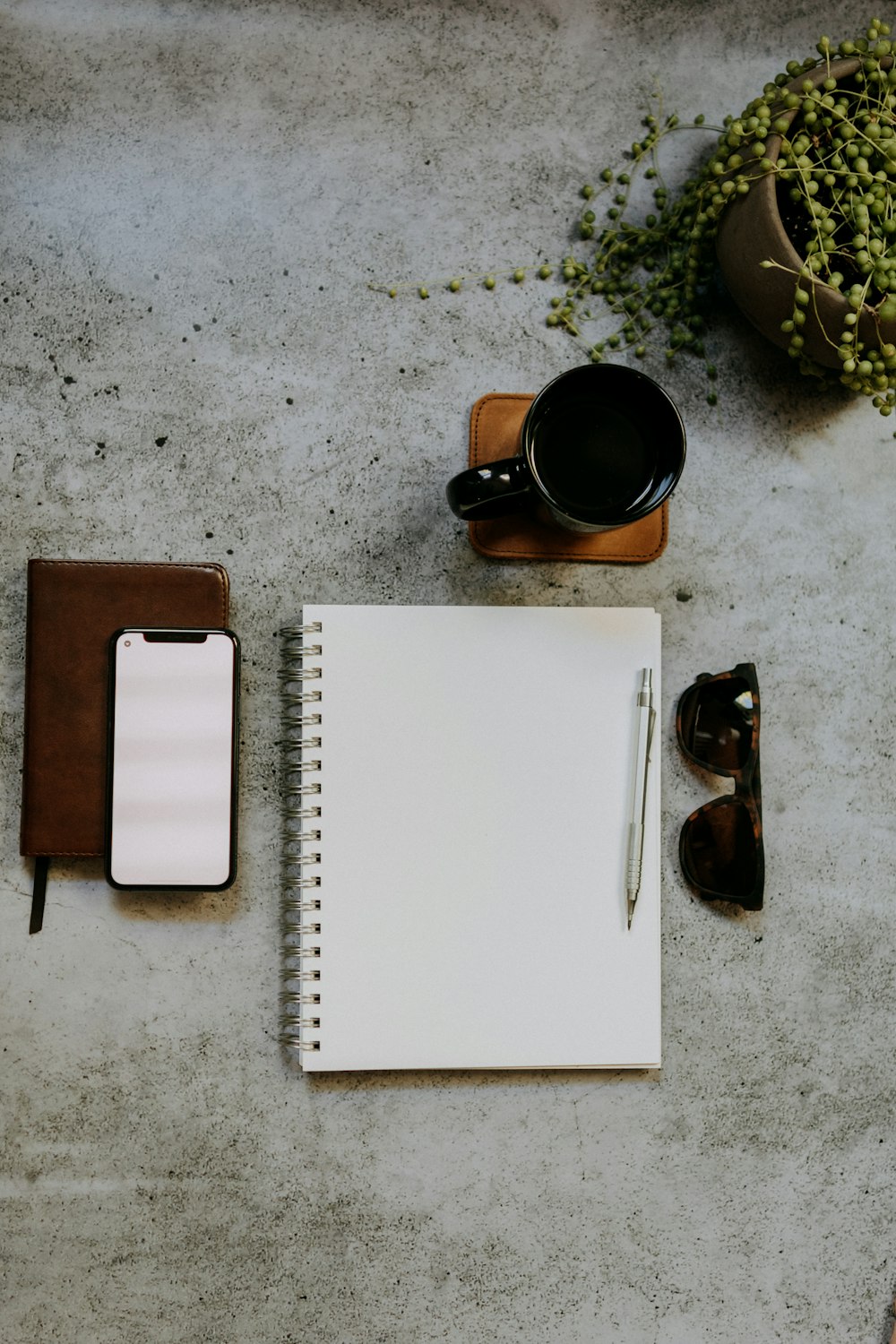 a notepad, pen, sunglasses, and a cup of coffee on a table