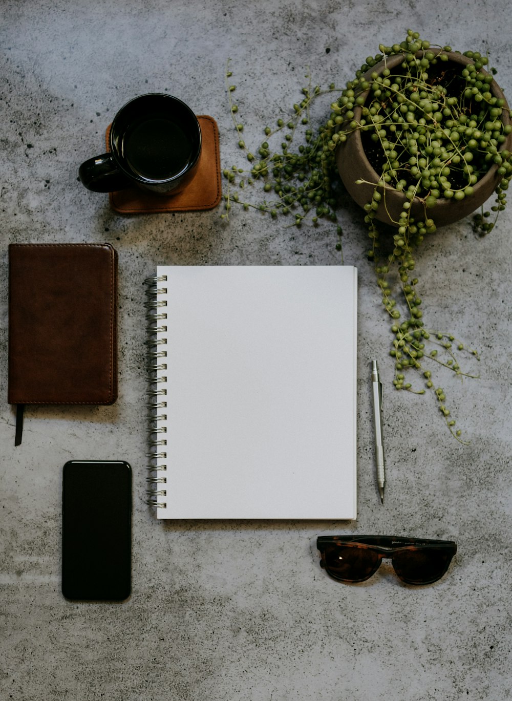 a notepad, pen, sunglasses, cell phone, and a cup of coffee