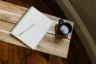 a cup of coffee and a pen on a wooden table