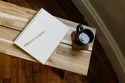 a cup of coffee and a pen on a wooden table
