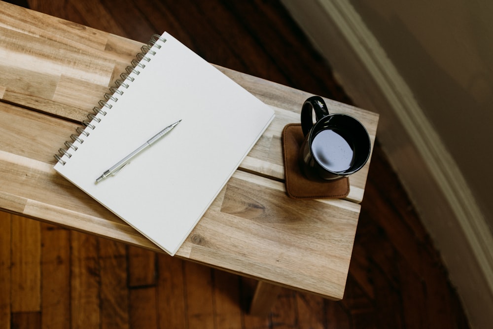 a cup of coffee and a pen on a wooden table