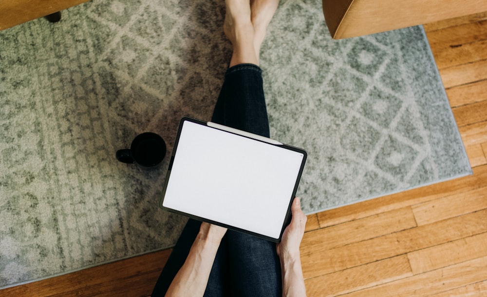 a person holding a tablet on a wooden floor