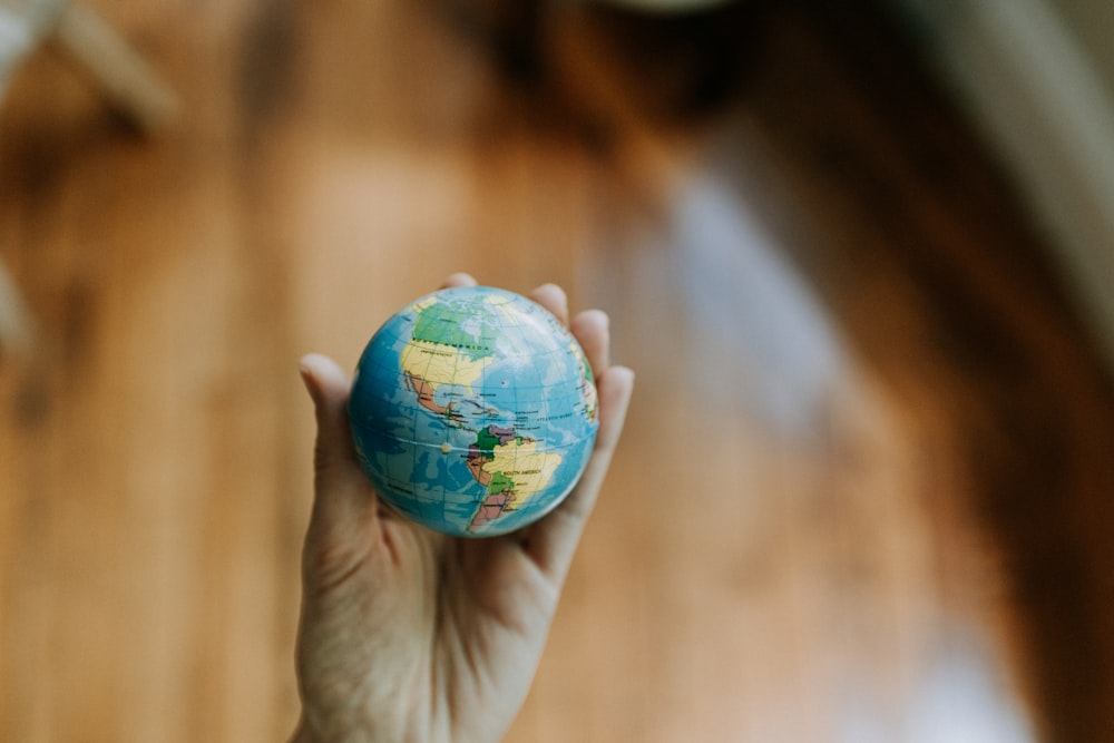 a person holding a small globe in their hand