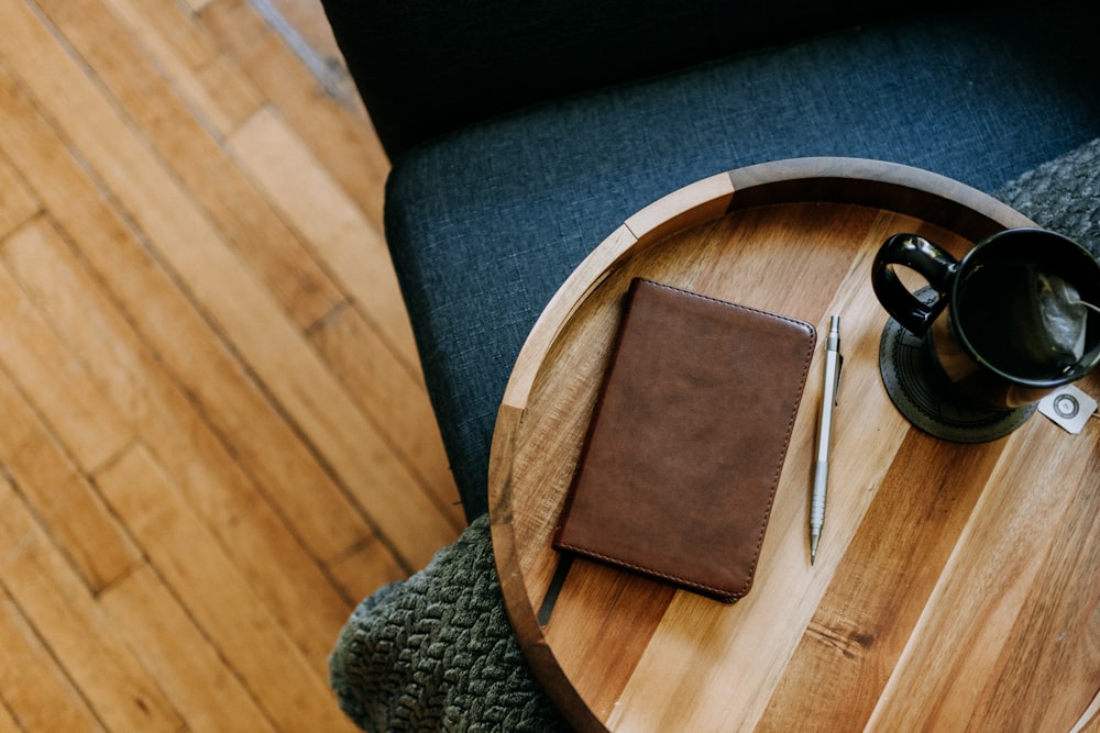a wooden table with a cup of coffee and a notebook on it
