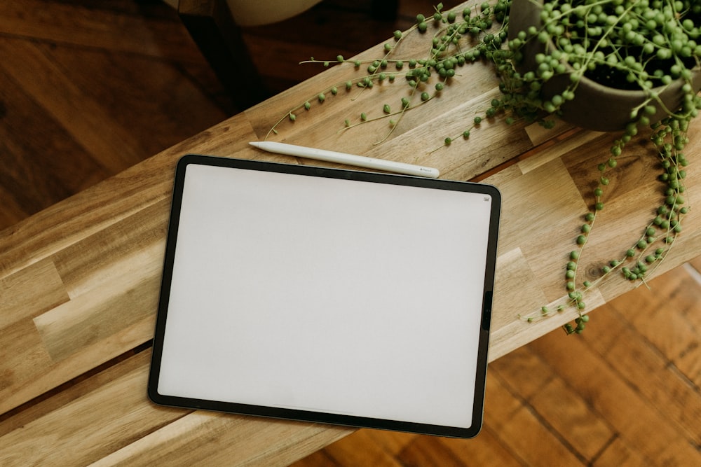 a wooden table topped with a white board next to a potted plant