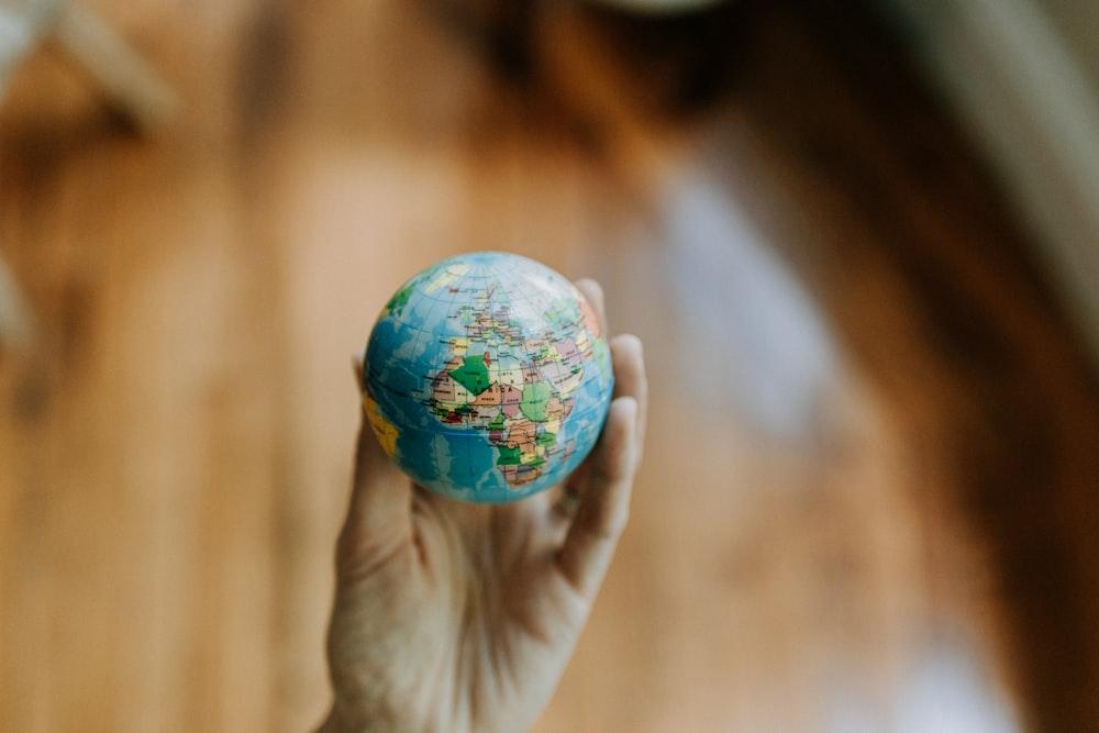 a person holding a small globe in their hand