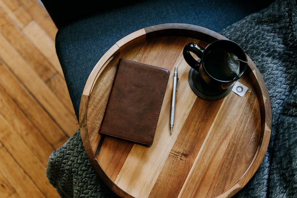 ein Holztablett mit einer Tasse Kaffee und einem Notizbuch darauf