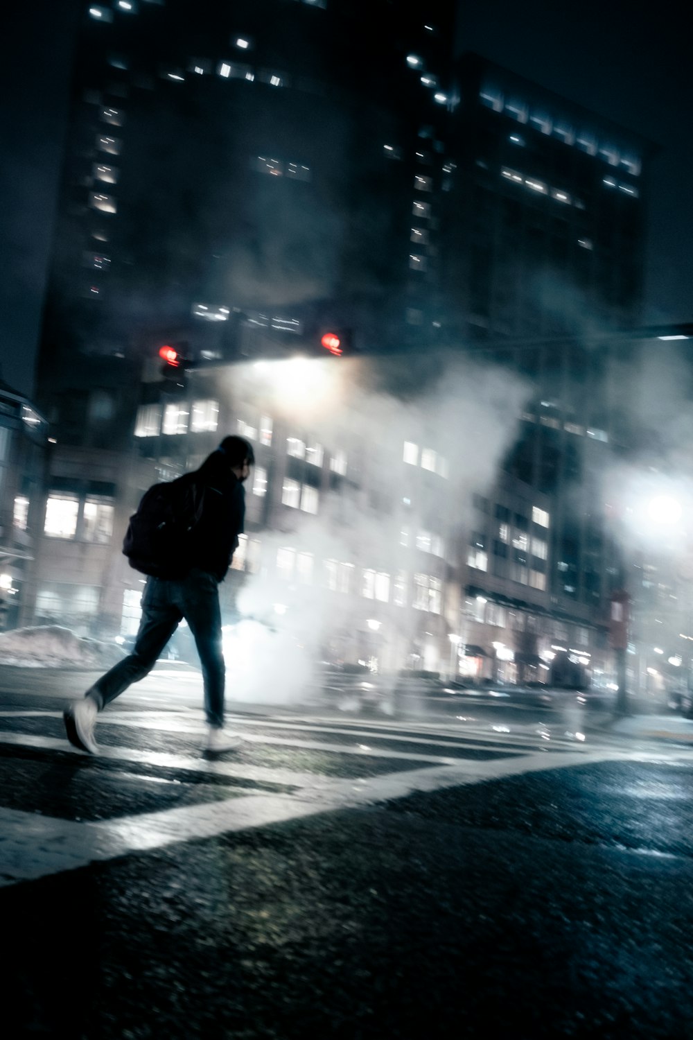 a man walking across a street at night