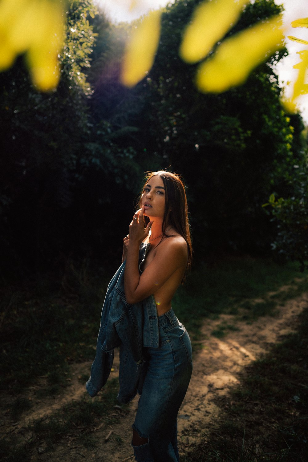 a woman standing on a dirt road talking on a cell phone