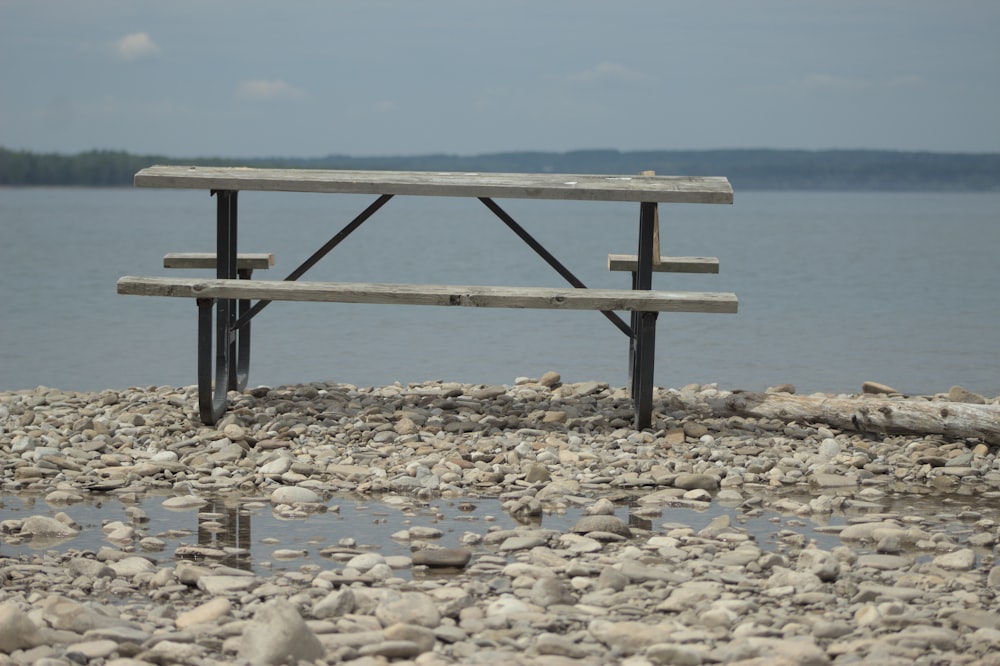 a wooden bench sitting on top of a rocky beach