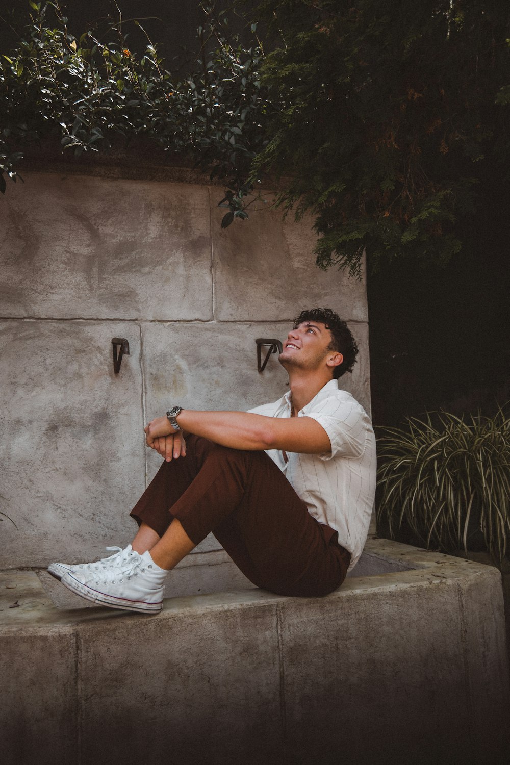 a man sitting on a ledge with his legs crossed