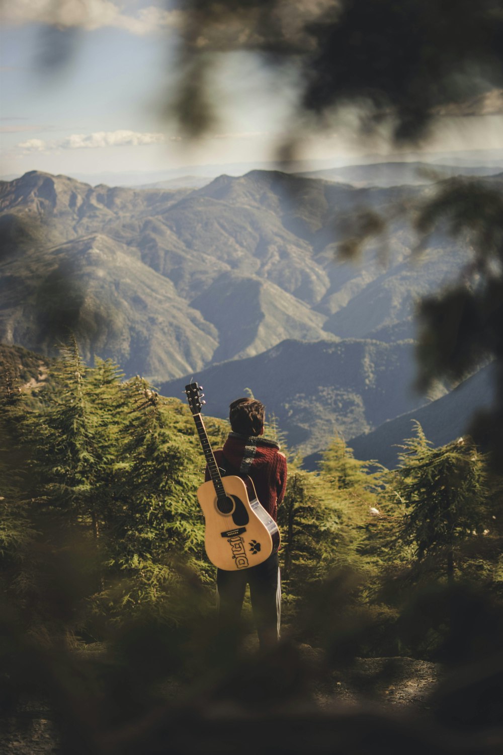 a man standing on top of a mountain holding a guitar