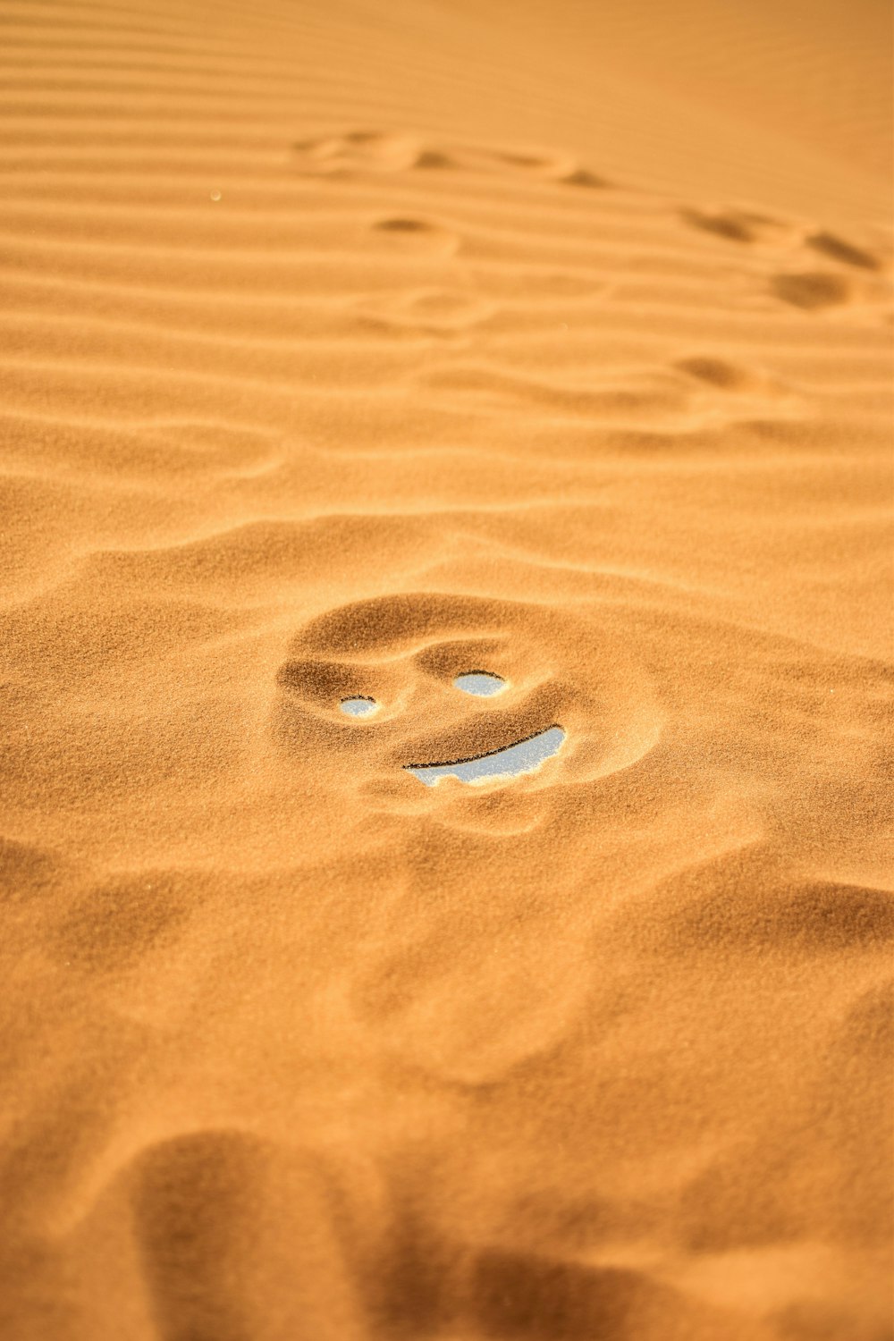 a smiley face drawn in the sand on a beach