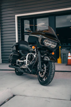 A sleek black and gold motorcycle escort leading a rider through a sunlit airport drop-off.