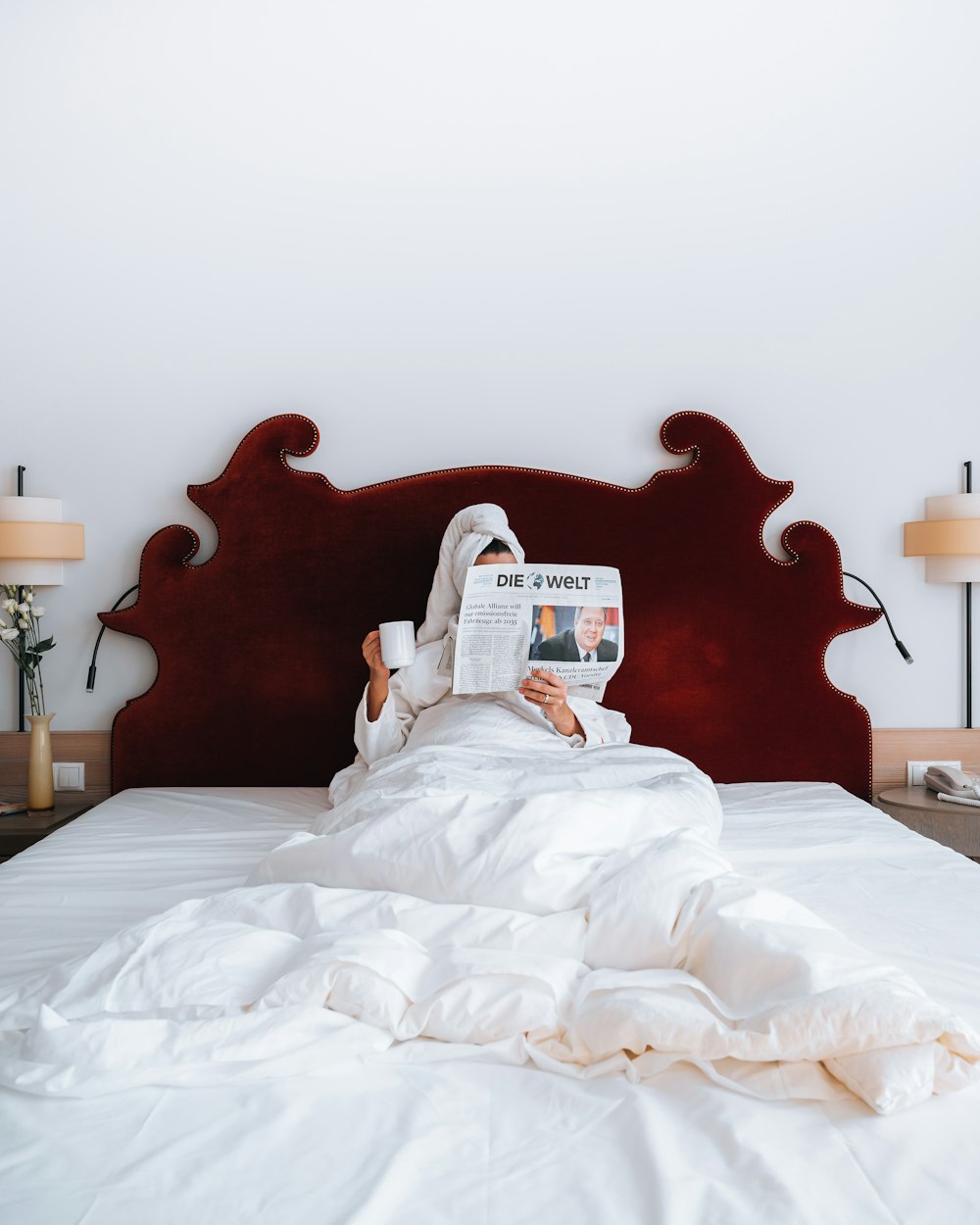 a person laying in bed reading a newspaper