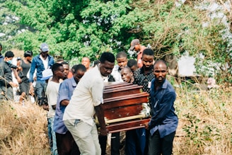 a group of people standing around a wooden casket