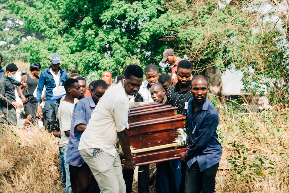 un groupe de personnes debout autour d’un cercueil en bois