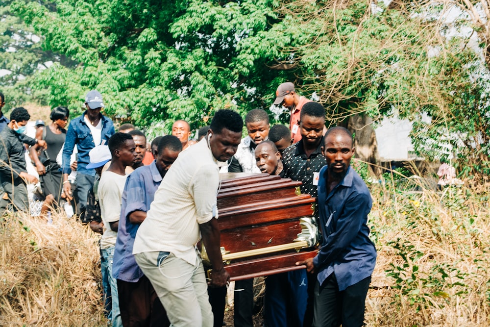 a group of people standing around a wooden casket