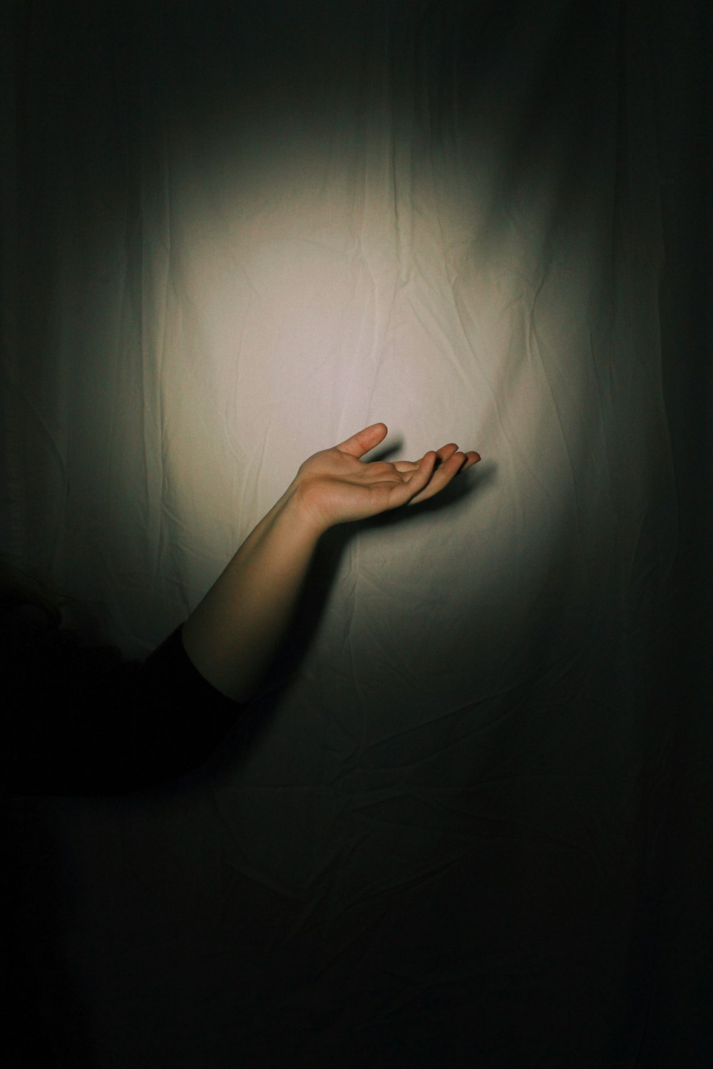 a person holding their hand out in the dark