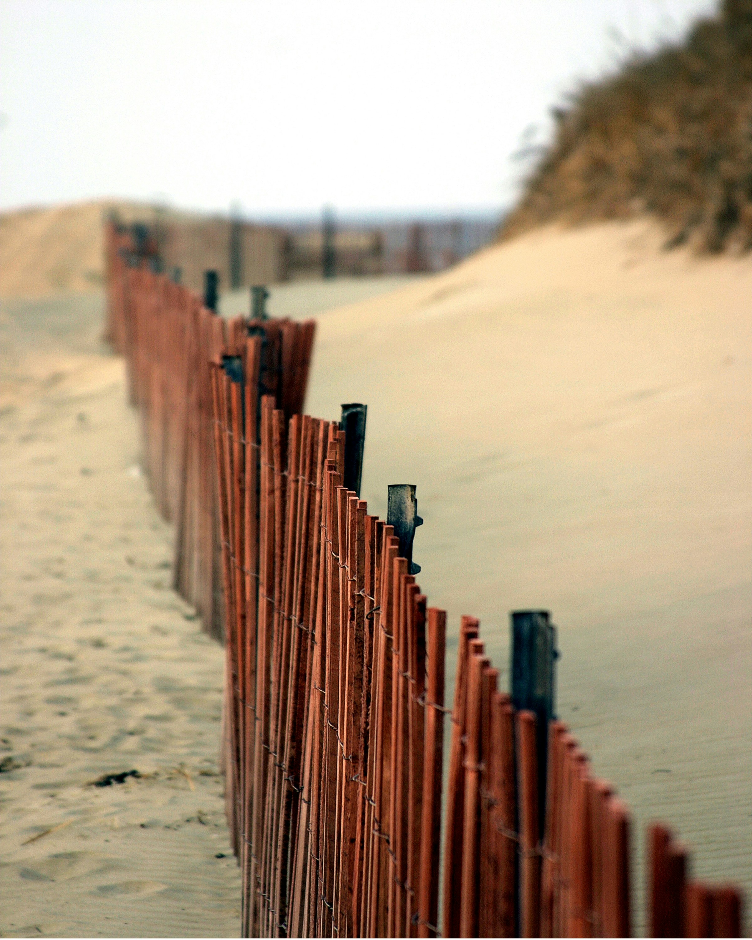 a red fence on a beach with sand behind it