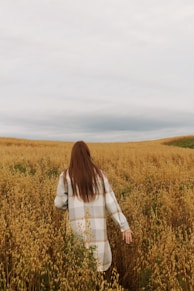a woman walking through a field of tall grass